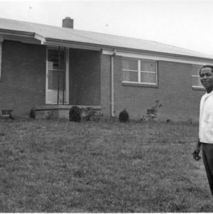 Unidentified man standing in front of a house