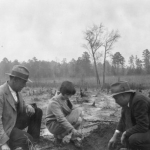 County Agent J.W. Sanders, Vance County, showing Erline Woodlief and her father how black walnut seedlings should be transplanted