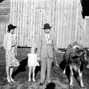 Dairy farmer J. C. Turner with wife, daughter, and two cows