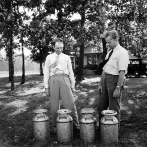 Dairy farmer J. C. Turner and farm agent J. E. Zimmerman examining milk cans