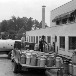 Men loading milk cans onto truck outside of Coble Dairy Plant