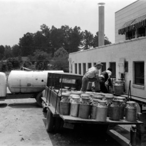 Men loading milk cans onto truck outside of Coble Dairy Plant