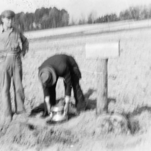 Horace E. Adcock and other placing milk in hole while waiting for milk truck