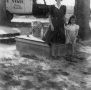 Mrs. Buchan and daughter delivering milk can to the milk truck