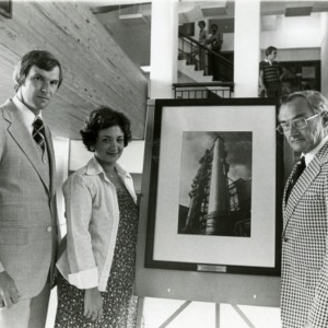 Three people in front of picture in gallery