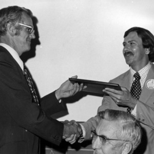 Two men with certificate shaking hands