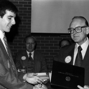 Two men with certificate shaking hands