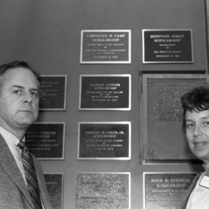 Man and woman in front of scholarship plaques