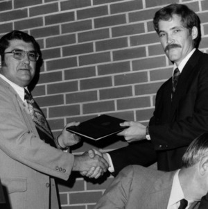 Two men with certificate shaking hands at Technical Association of the Pulp and Paper Industry meeting