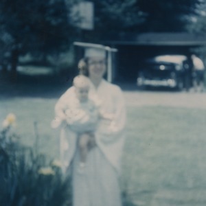 Marye Ann Fox in graduation robes and holding a baby