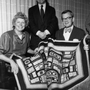 Mrs. Betty Poulton, J. Phillips Johnston, and Nicholas Bragg holding quilt