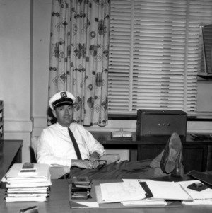 Henry A. Rutherford at desk, wearing captain's hat