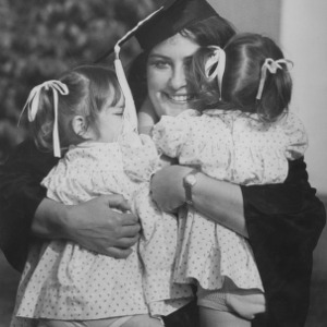 Graduate holding two young girls