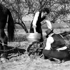 Professors examine a horse drawn planter and fertilizer distributor