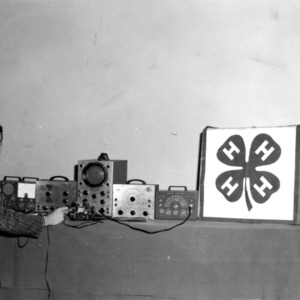 Student with electronics and 4-H banner