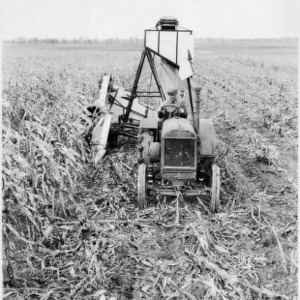 Worker using McCormick-Deering tractor and corn picker