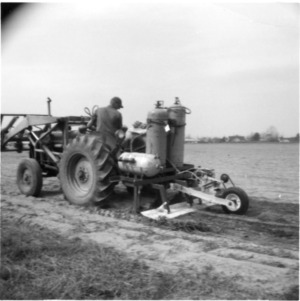 Worker on tractor with agricultural machinery in field