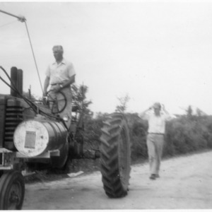 Man on tractor with man behind him