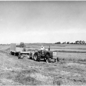 Man operating tractor and hay baler