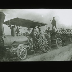 Steam-powered tractor hauling apples, circa 1900