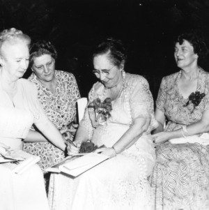 Judge Camille Kelley autographing one of her books with Mrs. George (Beulah) Apperson, Mrs. Harriett Pressly, and Miss Ruth Current