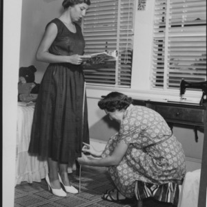 Woman measuring another's dress