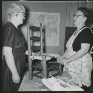 Women talk while applying wicker to a chair