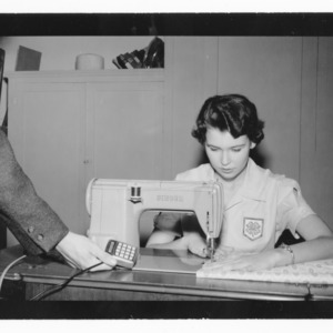 4-H Member Ella Margaret Bone at sewing machine with microphone